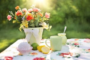 Blumenstrauß und Zitronen auf Gartentisch im Sonnenschein – stimmungsvolle Szene für ein Sommerfest im Garten