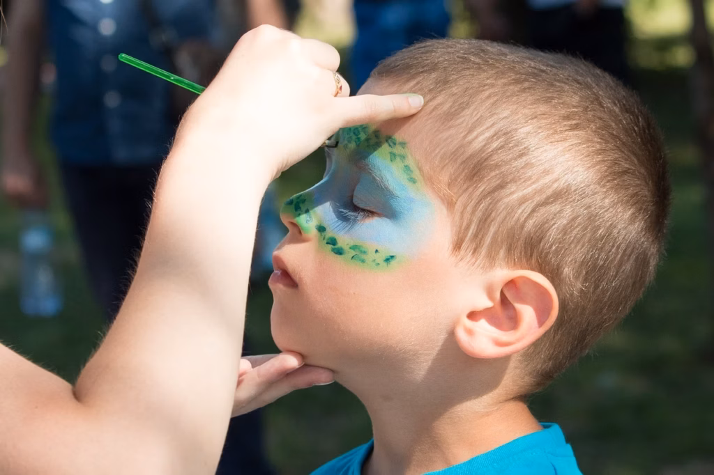 Junge bekommt ein fantasievolles Gesichtsmake-up beim Kinderschminken auf dem Sommerfest