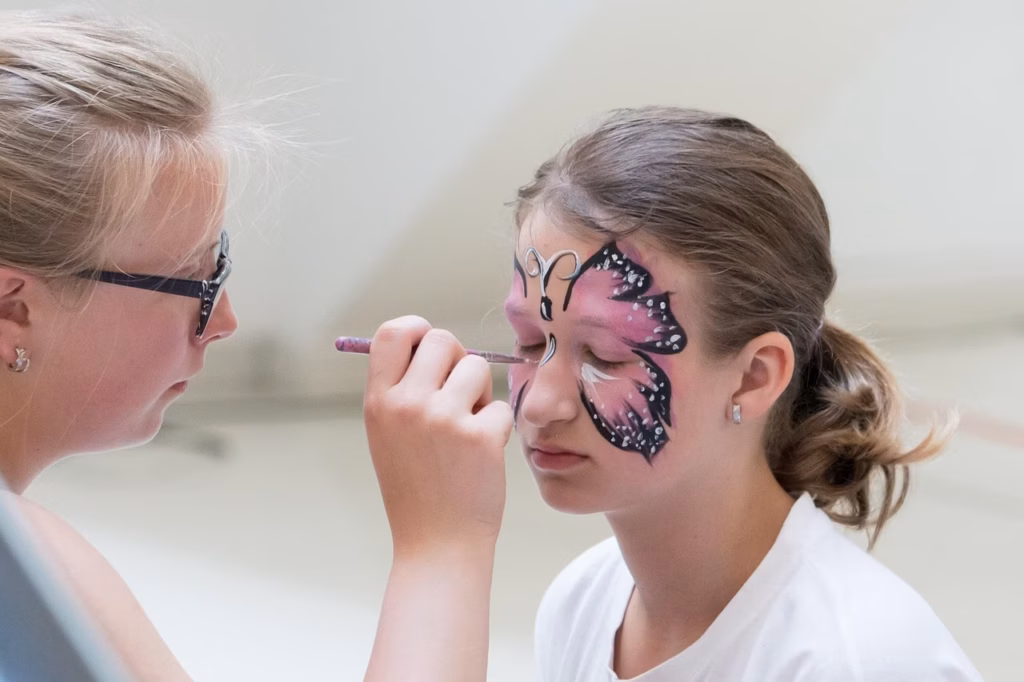 Mädchen wird als bunter Schmetterling geschminkt – beliebtes Kinderschminkmotiv