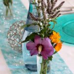 Bunte Sommerblumen als Tischdeko auf türkis gedecktem Tisch beim Sommerfest